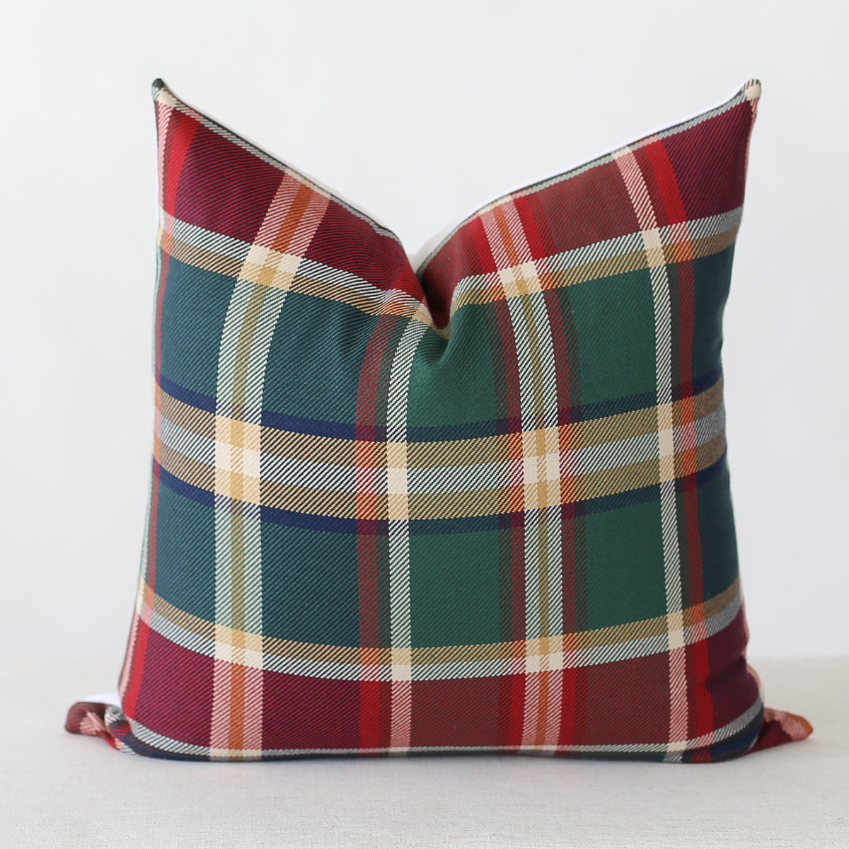 This pillow features a classic tartan plaid pattern with rich hues of deep green, red, cream, and hints of navy and mustard, creating a warm, traditional look.