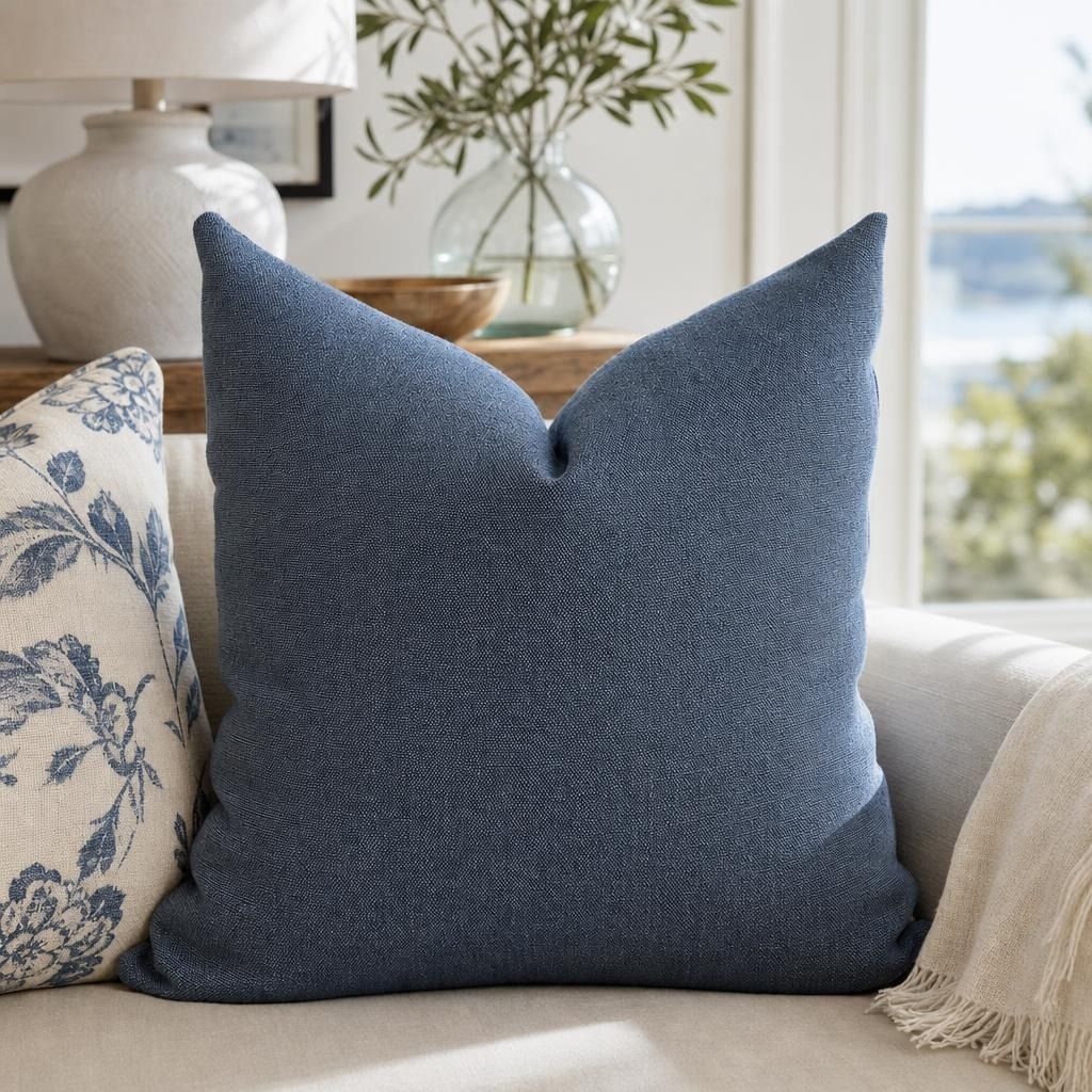 Ambrose Pillow Cover in dark blue linen styled on a neutral sofa in a contemporary living space.