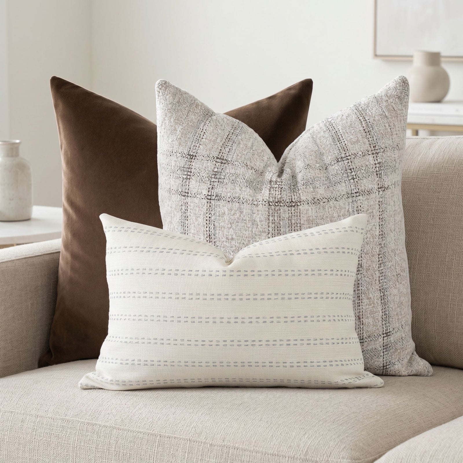 Bennett sofa pillow set with velvet and plaid on a neutral sofa in a bright, airy living space.
