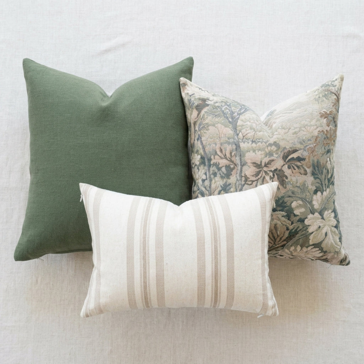 Flat-lay image of three Callahan pillows in different sizes with stripe and botanical patterns, showcasing seamless hidden zippers on textured white background.