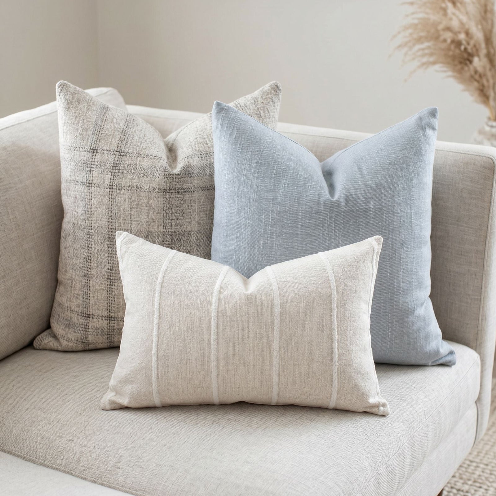 Detailed view of Bennett pillow set on textured sofa, highlighting subtle patterns, hidden zippers, and calming cream and blue tones in a spacious room.