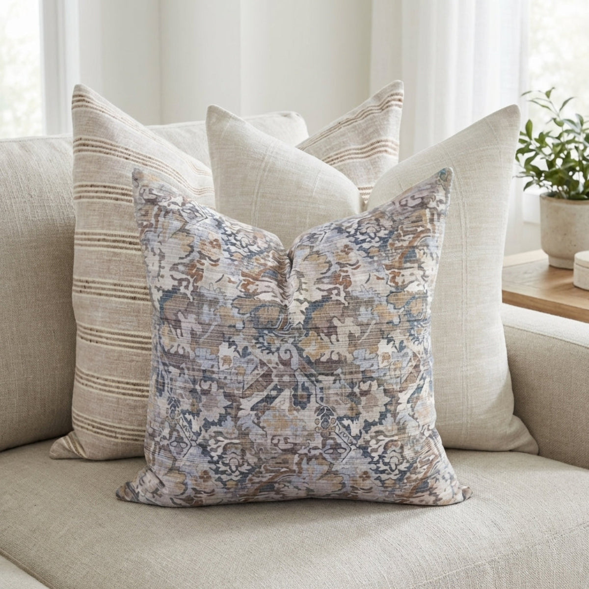 Full-view of a cozy sofa decorated with the Single-Sided Combo 9 pillows in a bright, neutral space highlighting layered textures and a refined aesthetic.