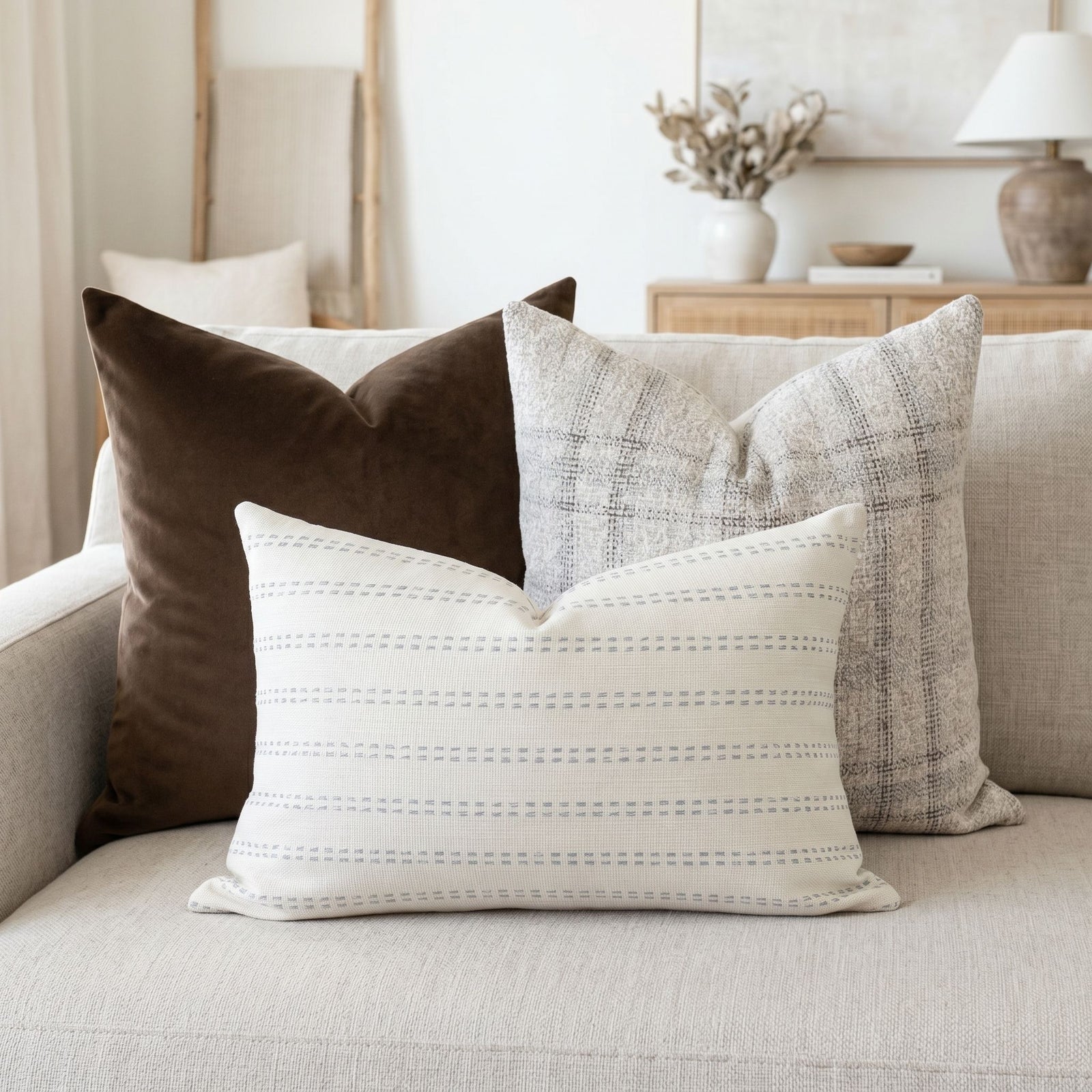 Bennett sofa pillow set with velvet and plaid on a neutral sofa in a bright, airy living space.