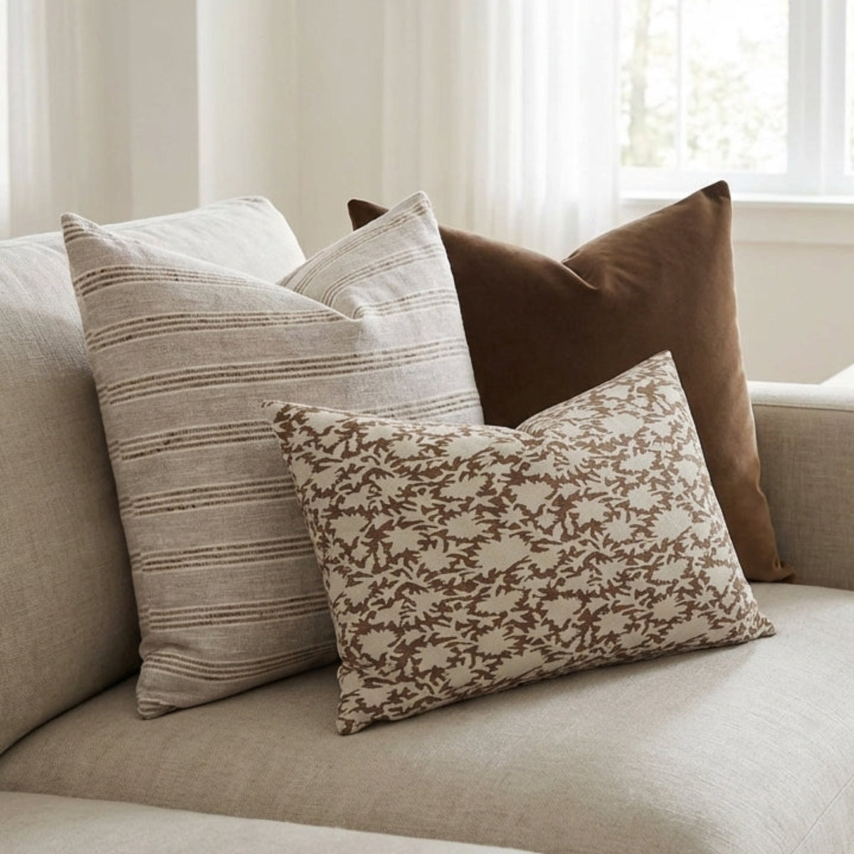 Full view of Oversized Combo 4 pillows on a neutral-toned sofa in a bright, airy living space, showcasing design and texture.