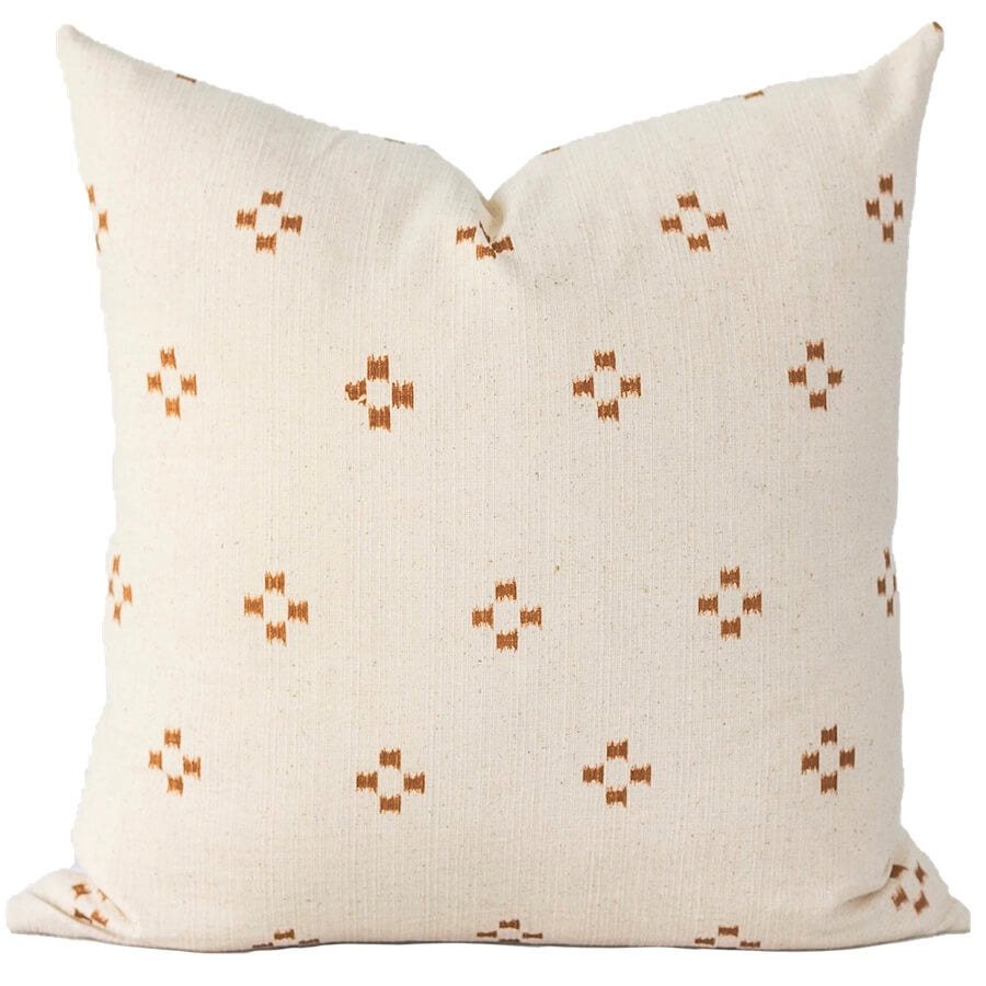 A light cream pillow adorned with a simple geometric orange cross-stitch pattern, crafted from a slightly textured Hmong cotton fabric.