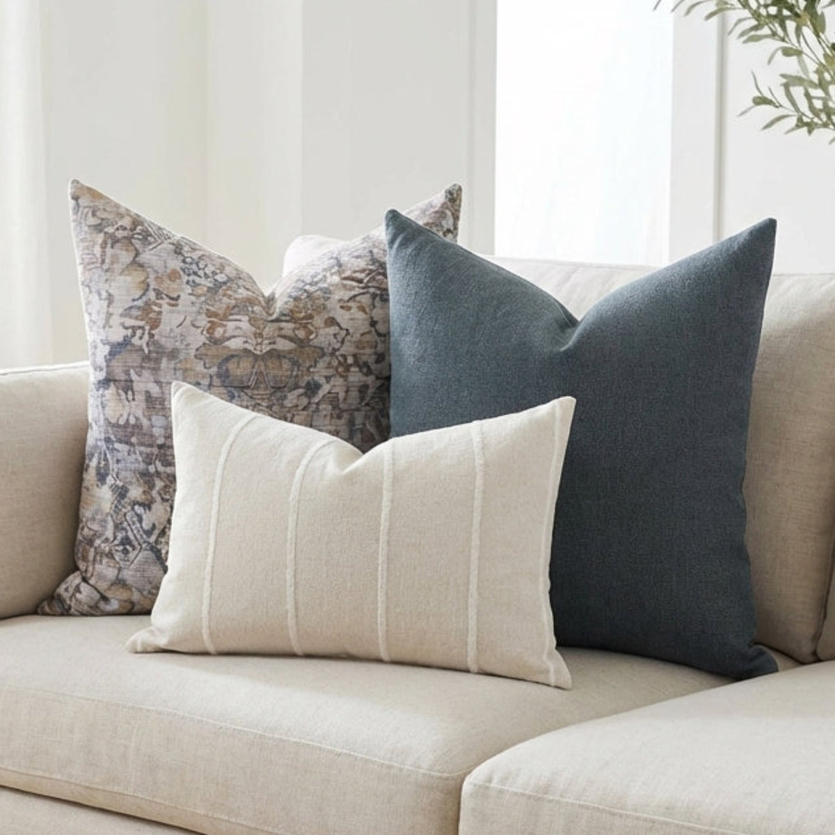 Full view of sofa with 'Mixed Combo 3' pillows in a modern, airy living room, showcasing different sizes, textures, and neutral tones.