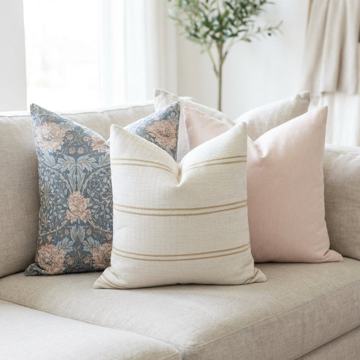 Set of three pillow covers styled on a neutral-toned sofa in a bright, airy living space, showcasing intricate patterns and textures with hidden zippers.