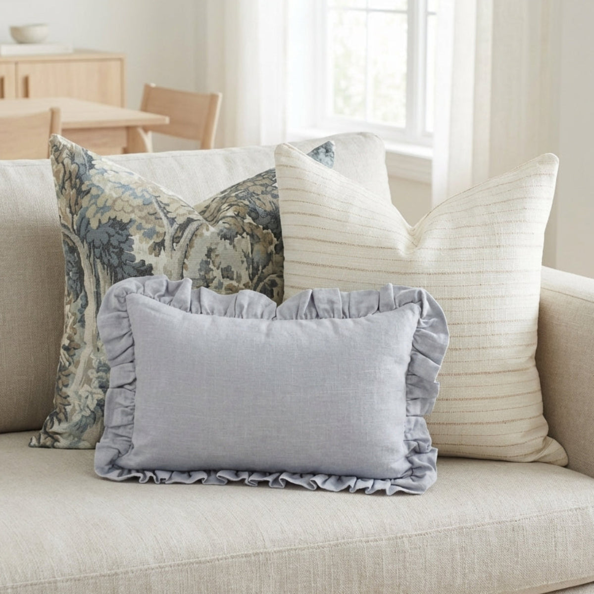 Realistic shot of Ronan Pillow Combo 4 on a neutral-toned, airy sofa showcasing textures and ruffled edge with soft lighting.