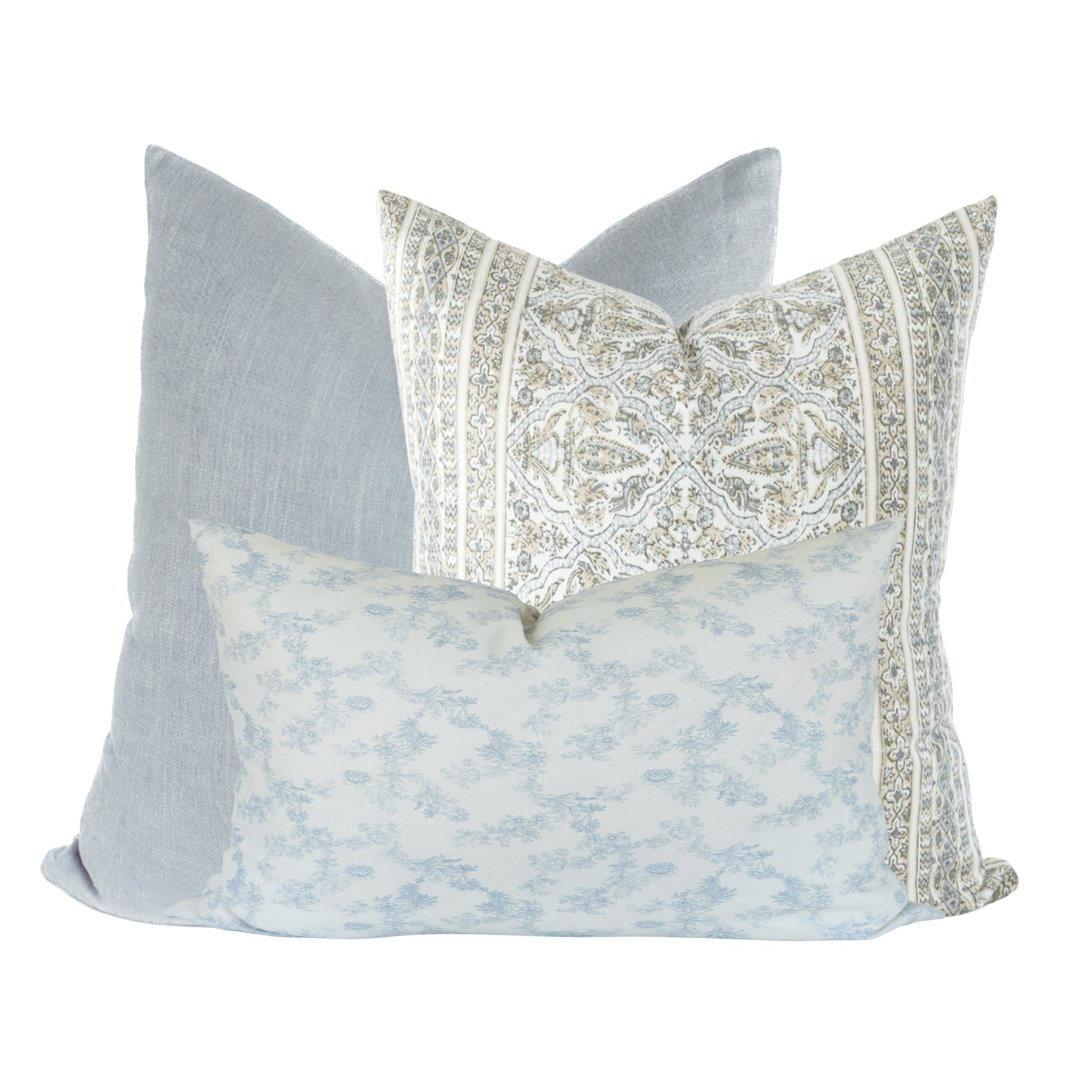 Close-up of Ronan, Athena, and Charlotte pillow covers on a neutral-toned sofa in a bright, airy living space, highlighting textures and patterns.
