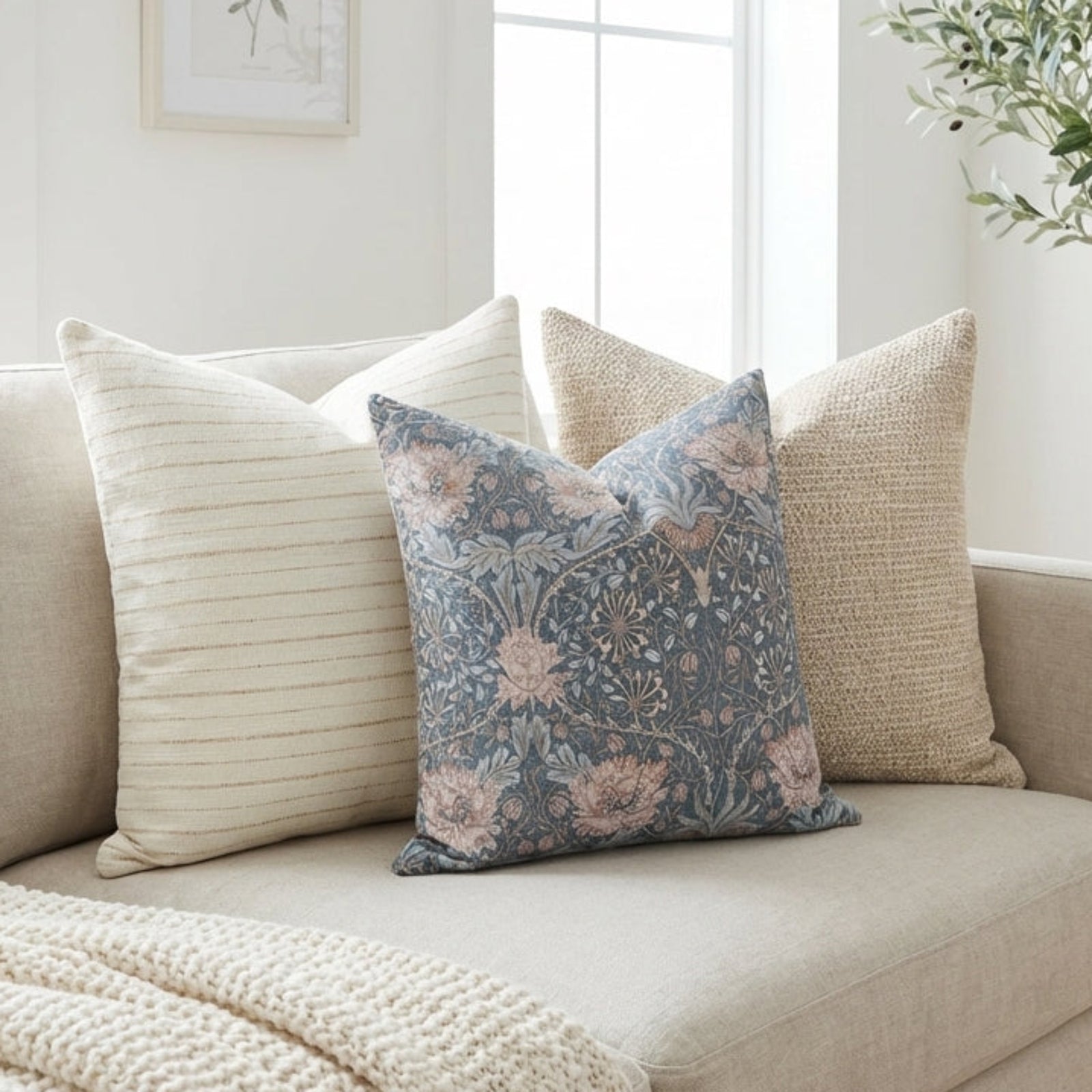 Pillow arrangement on a neutral-toned sofa featuring Wyatt striped, Ridley textured, and Marlow floral pillow covers in a light, airy living space.