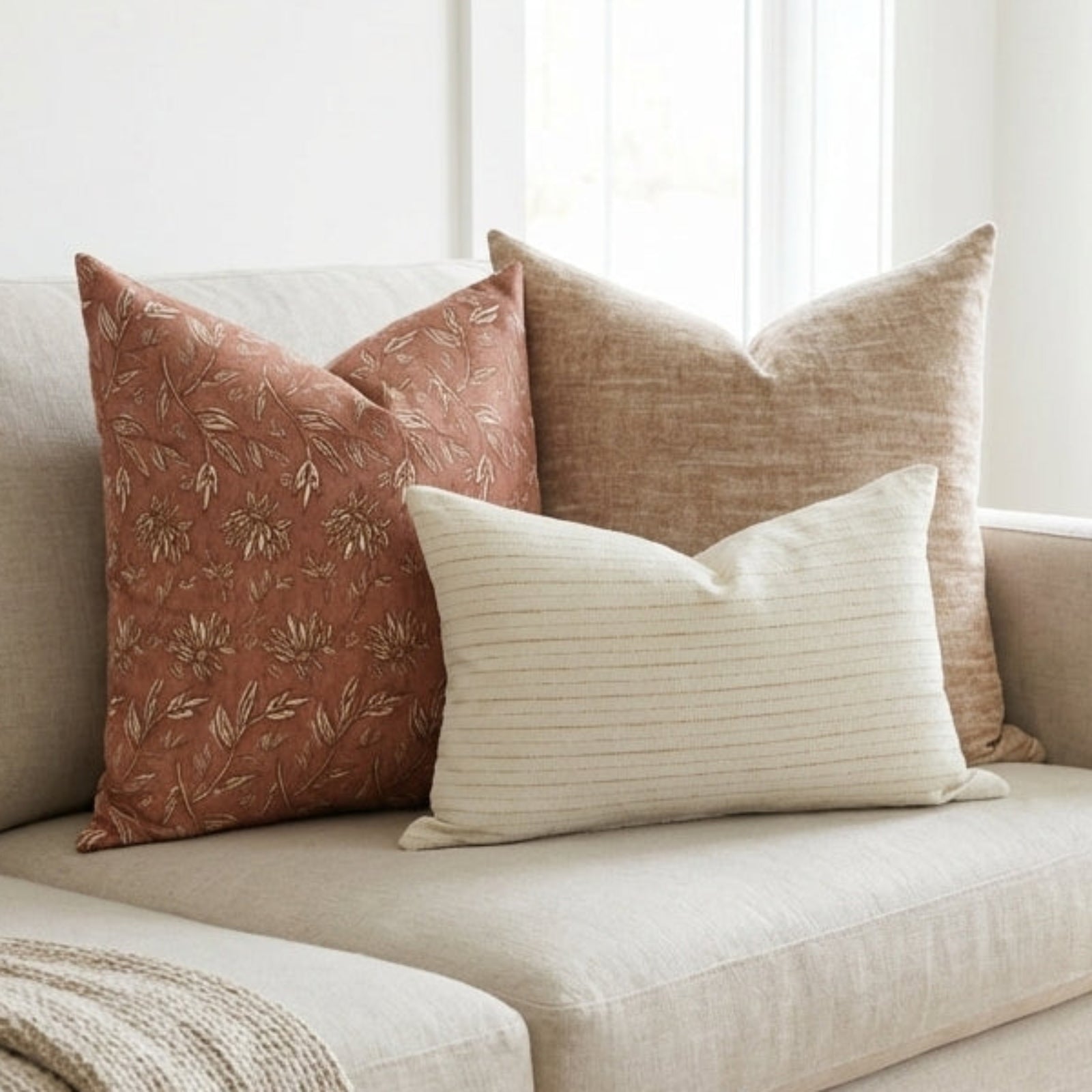 Close-up of a textured terracotta floral pillow cover on a neutral-toned sofa, highlighting its subtle pattern, fabric details, and discreet zipper.